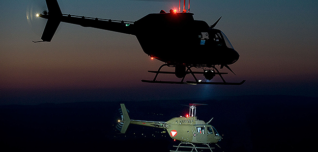Zwei Hubschrauber fliegen bei Nacht.