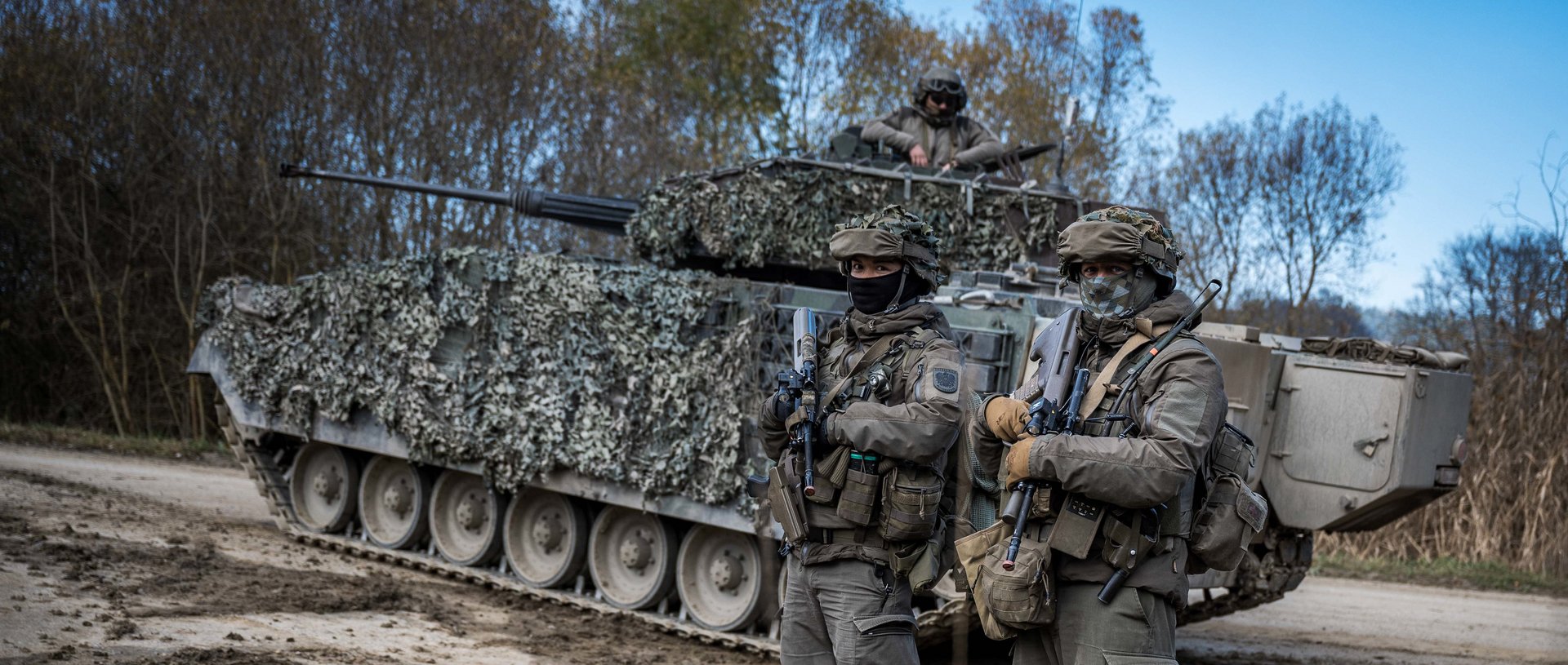 2 Soldaten stehen vor einem Schützenpanzer "Ulan".