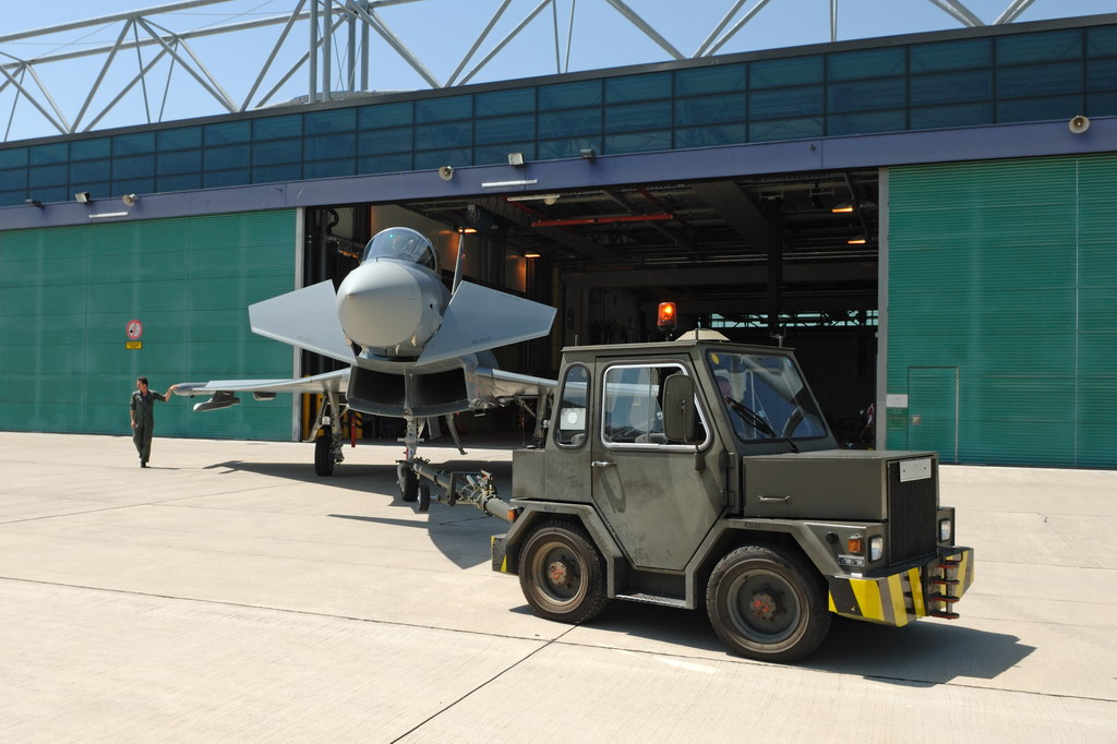 Ein Eurofighter wird von einem Zugfahrzeug aus dem Hangar gebracht.
