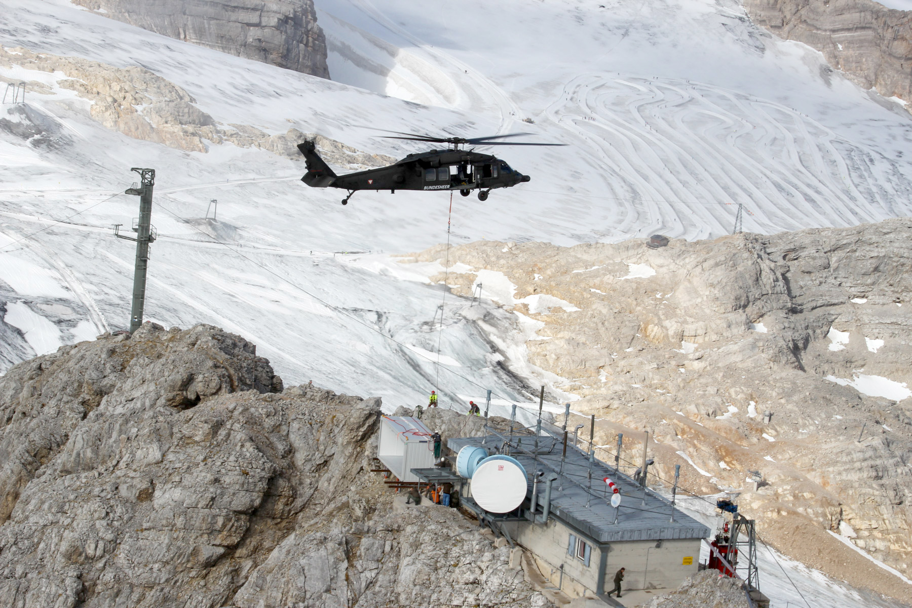 Ein "Black Hawk"-Hubschrauber fliegt über eine Funkstation im Gebirge.