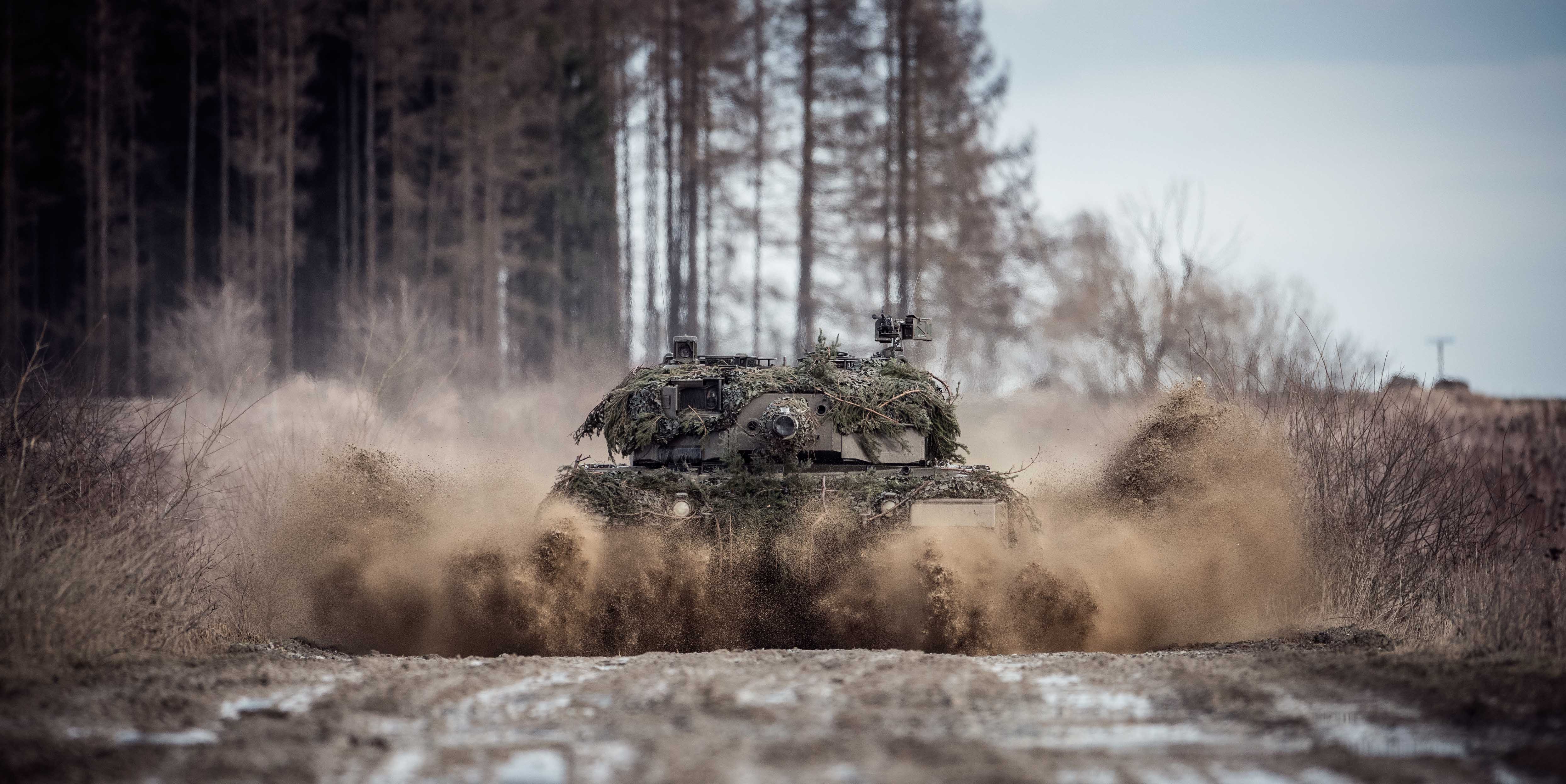 Ein Kampfpanzer "Leopard" 2A4 fährt durch eine Lacke.