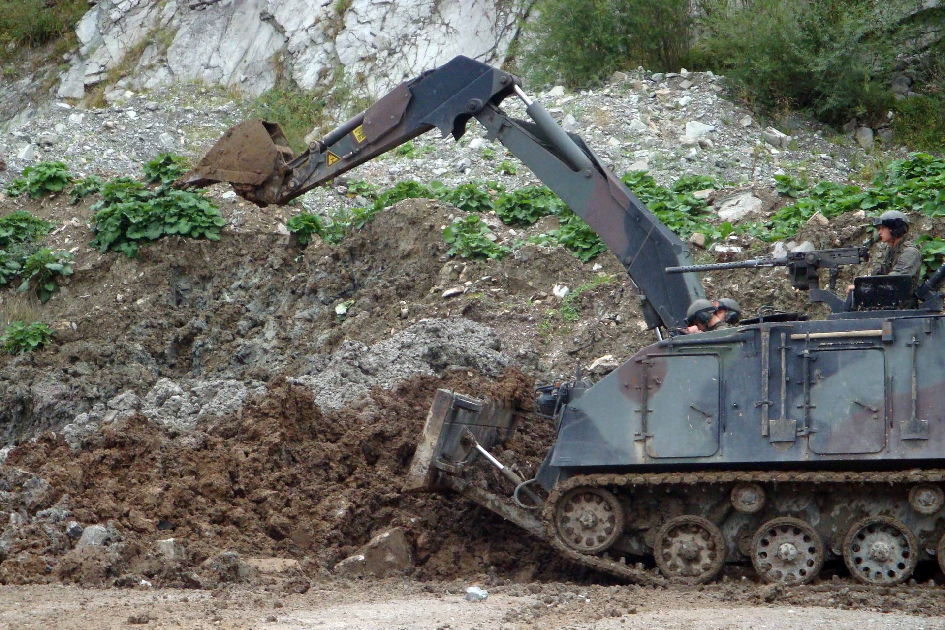 Ein Pionierpanzer räumt Erde bei Seite.