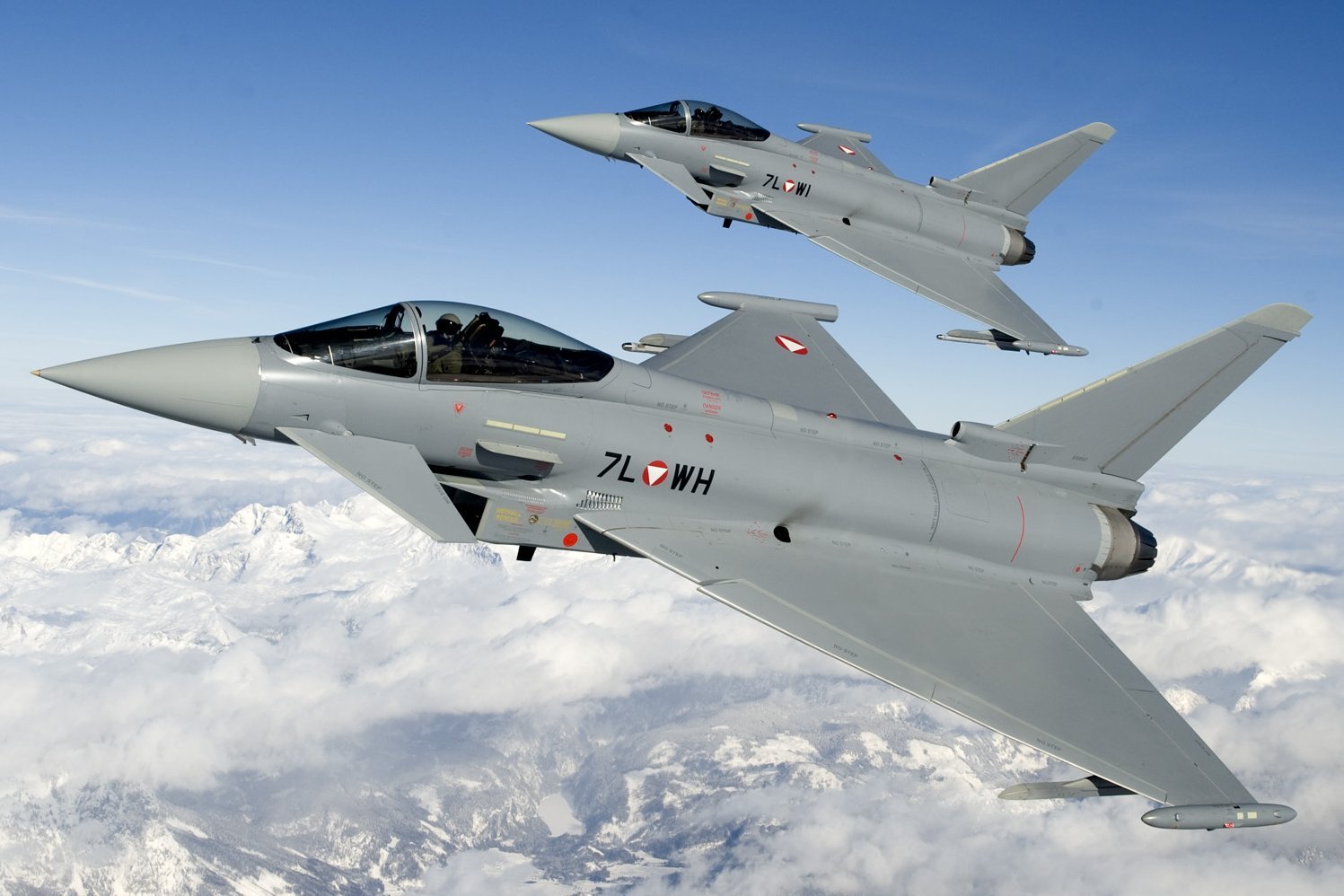 Zwei Eurofighter fliegen über verschneiten Bergen im Westen Österreichs.