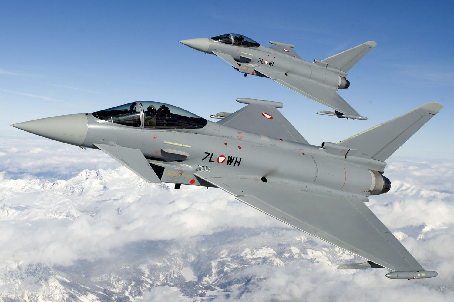 Zwei Eurofighter fliegen über verschneiten Bergen im Westen Österreichs.