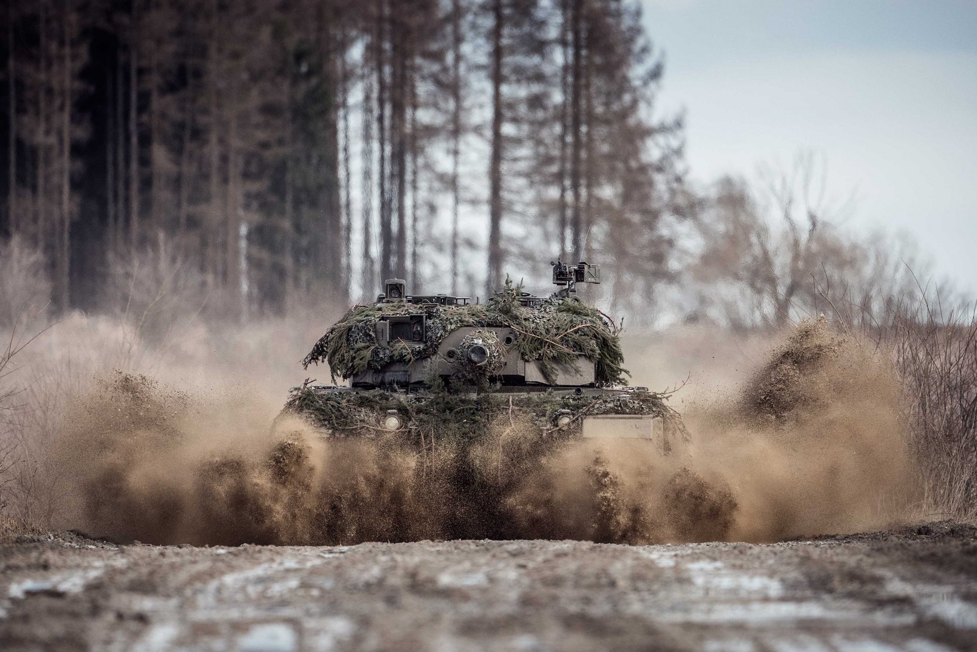 Ein Kampfpanzer "Leopard" 2A4 fährt durch eine Lacke.