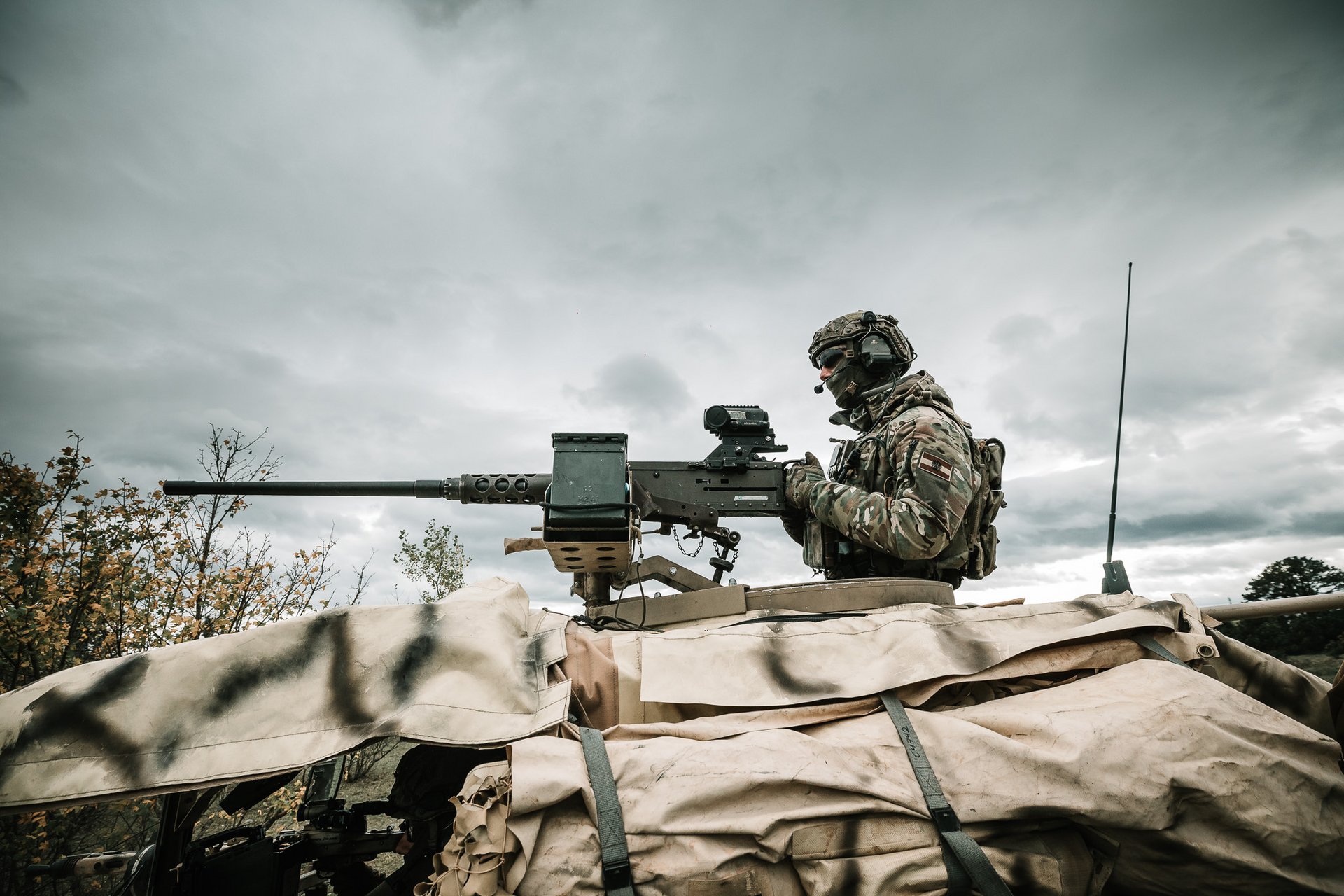 Ein Soldat des Jagdkommandos mit einem überschweren Maschinengewehr, das am Dach eines Fahrzeugs befestigt ist.