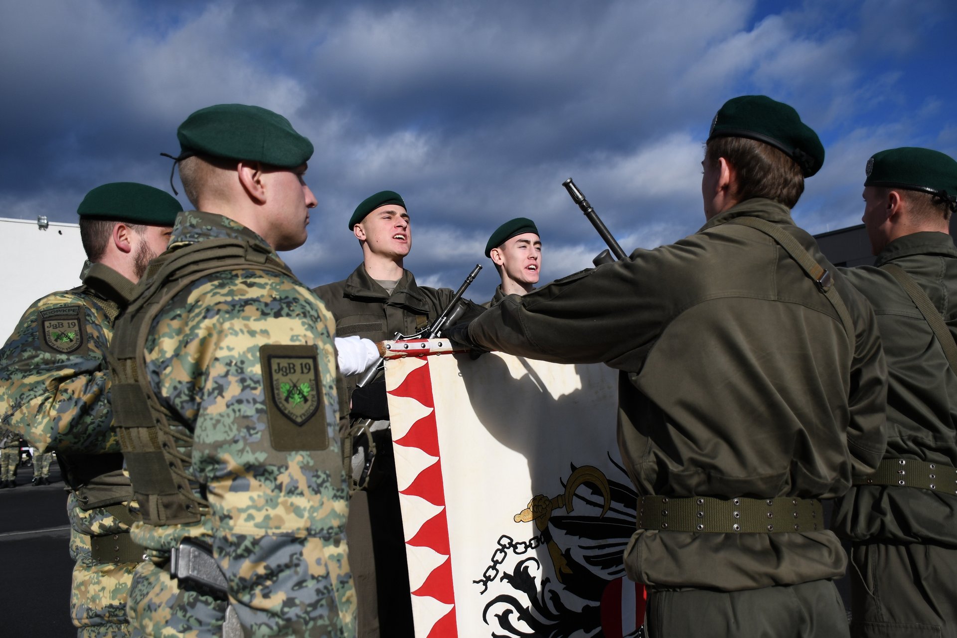 Vier Rekruten leisten ihr Gelöbnis mit der Hand an der Insignie.