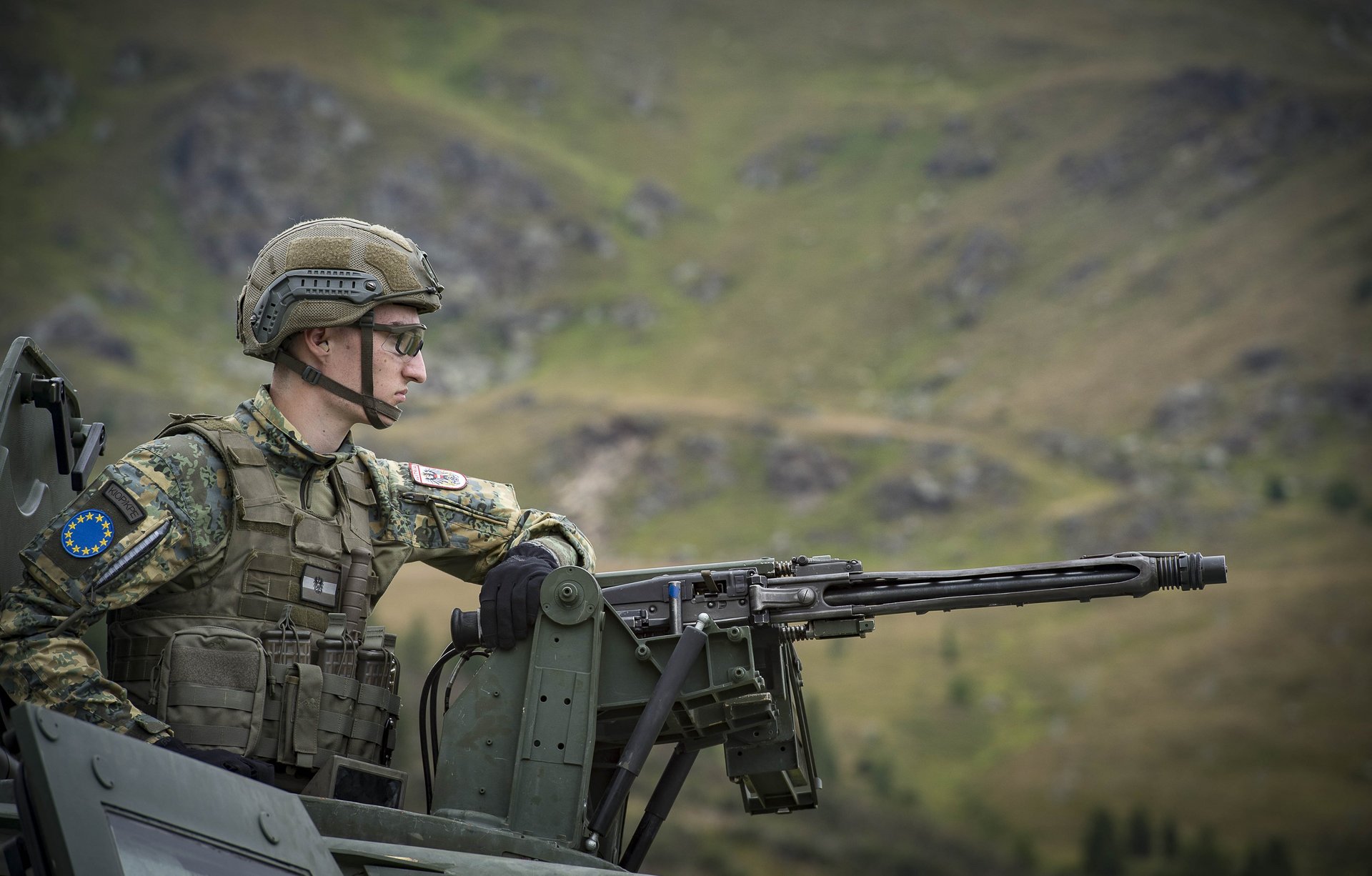 Ein Soldat mit Maschinengewehr auf einem gepanzerten Fahrzeug.