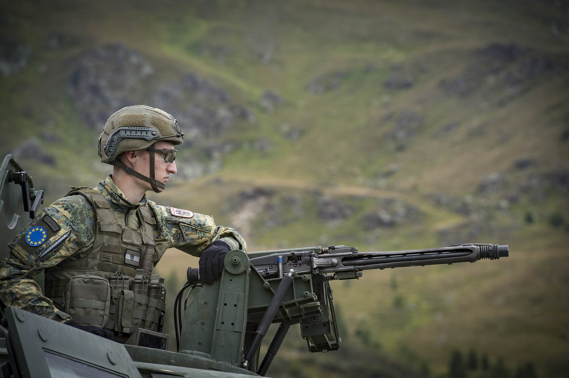 Ein Soldat mit Maschinengewehr auf einem gepanzerten Fahrzeug.