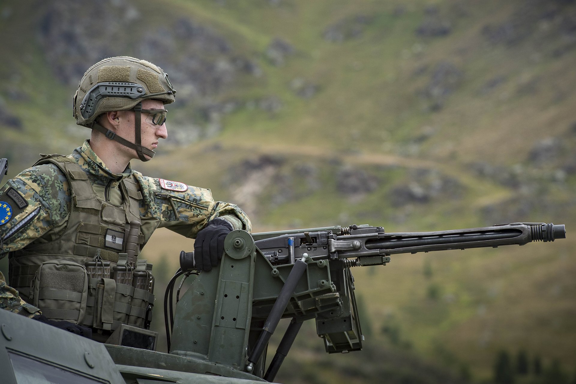 Ein Soldat mit Maschinengewehr auf einem gepanzerten Fahrzeug.