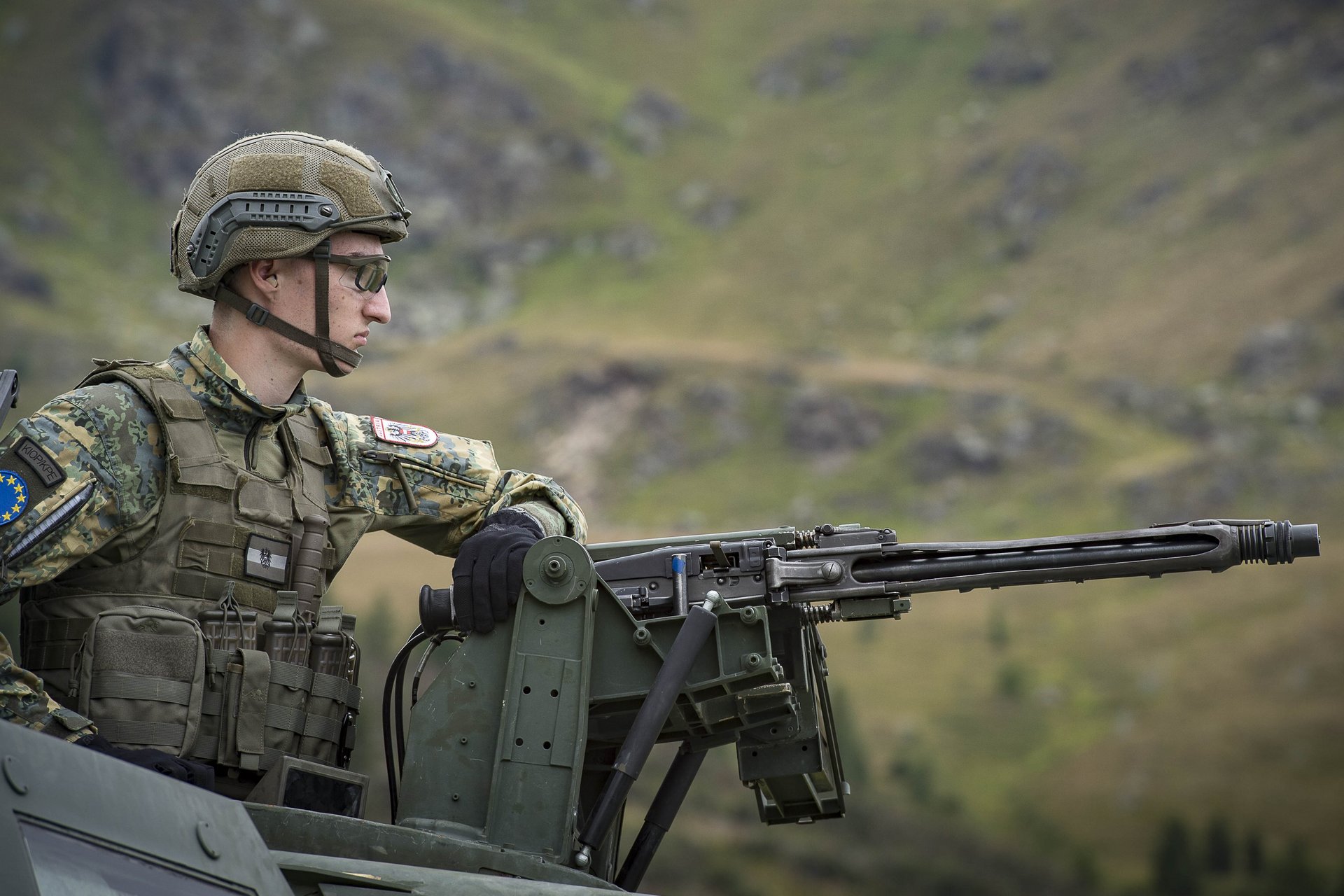 Ein Soldat mit Maschinengewehr auf einem gepanzerten Fahrzeug.