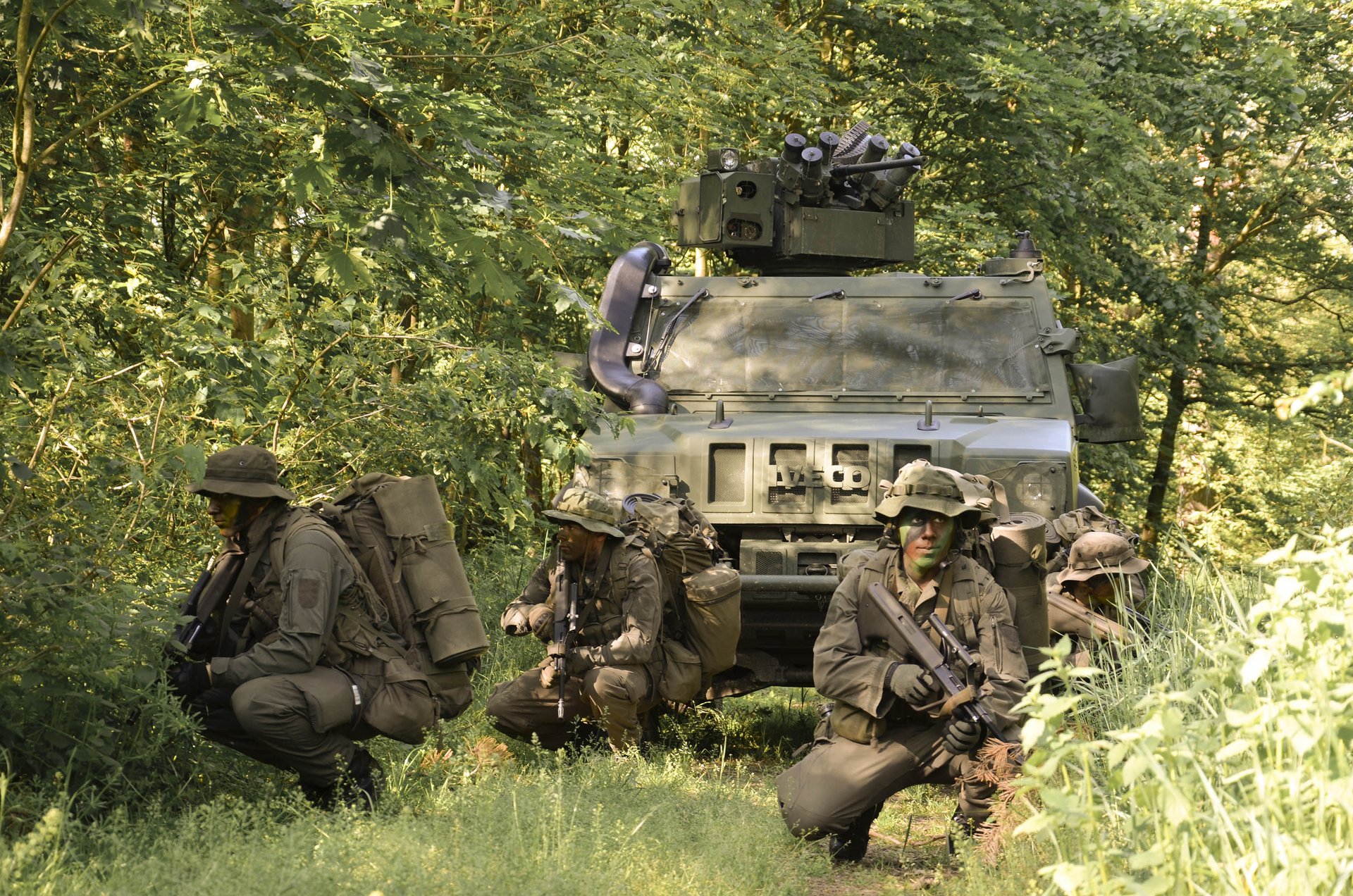 Soldaten des Aufklärungs- und Artilleriebataillons 4 gehen im Schutz eines Husar-Fahrzeuges vor.