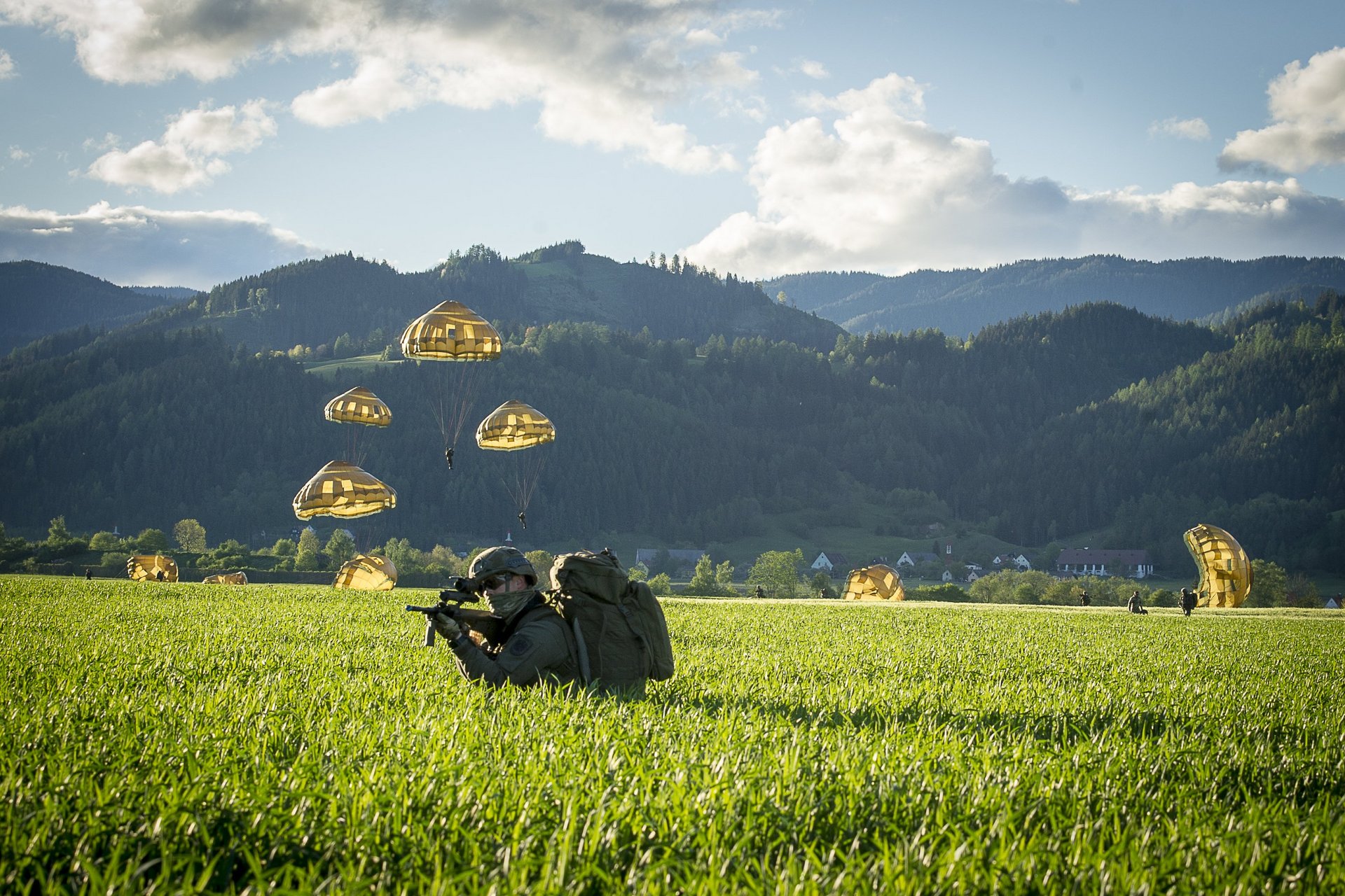Soldaten landen mit Fallschirmen in einem Feld.
