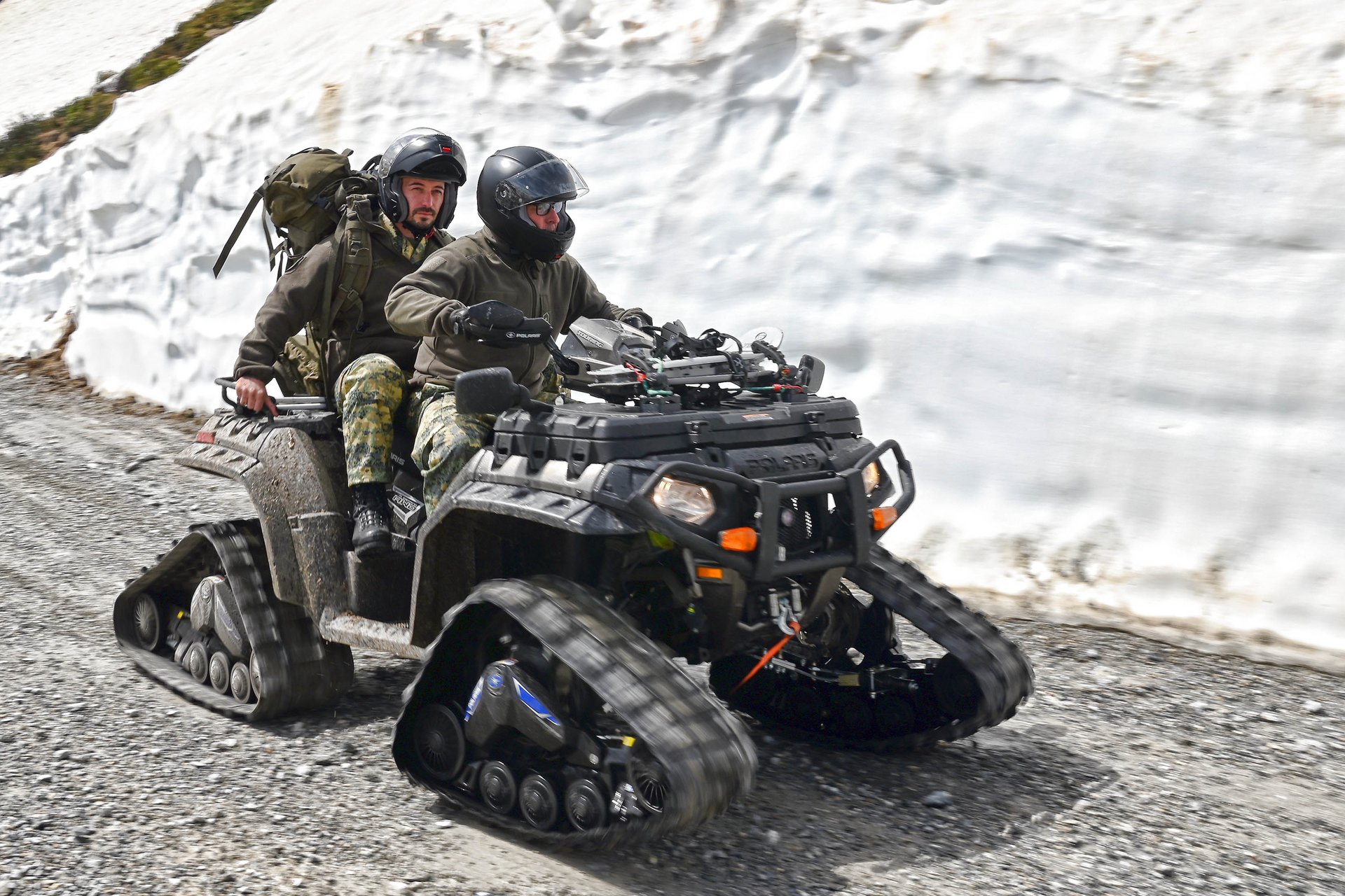 2 Soldaten fahren auf einem Quad einen Weg im Gebirge entlang.