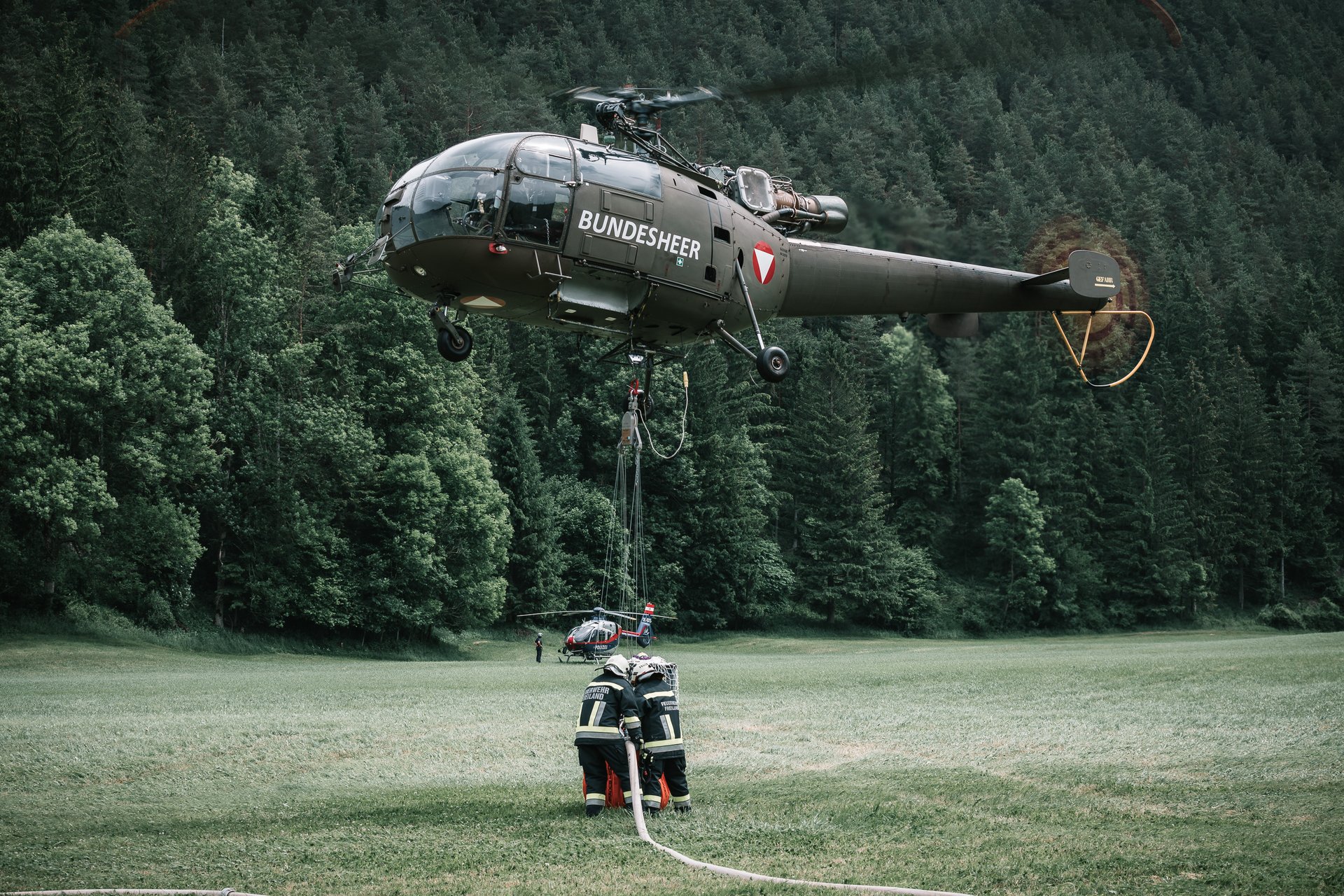 Ein "Alouette"-Hubschrauber nimmt einen Wasserbehälter auf, um einen Waldbrand zu bekämpfen.