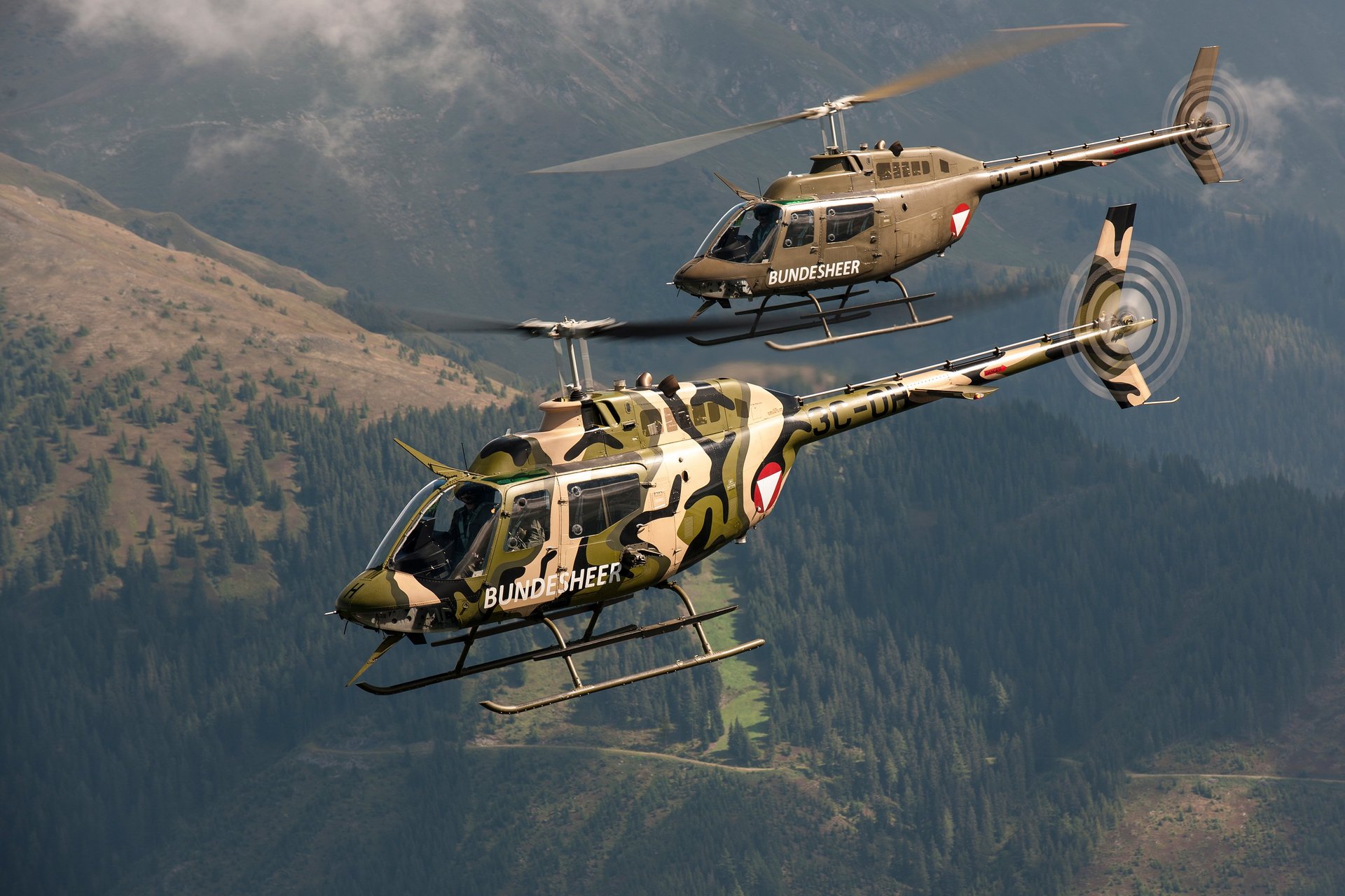 Zwei Bell OH-58 "Kiowa" im Flug, einer mit Speziallackierung.