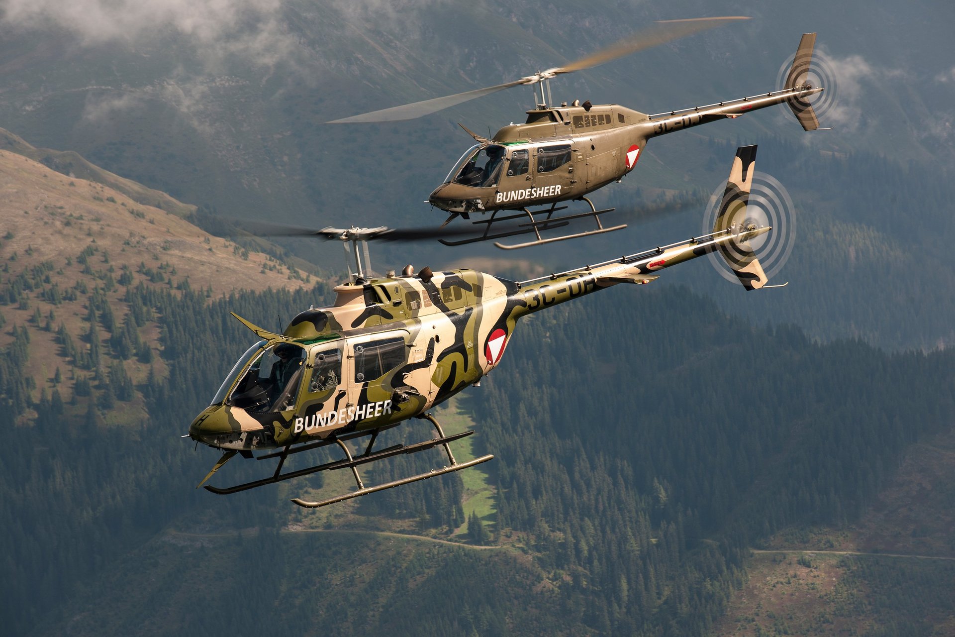 Zwei Bell OH-58 "Kiowa" im Flug, einer mit Speziallackierung.