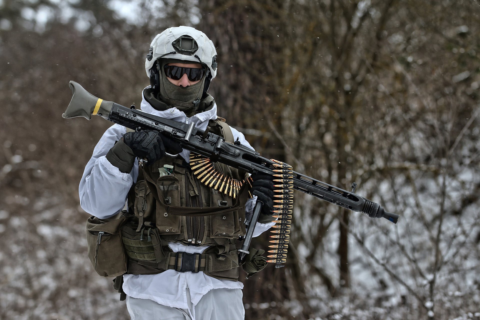 Ein Soldat im weißen Wintertarnanzug trägt ein Maschinengewehr 74.