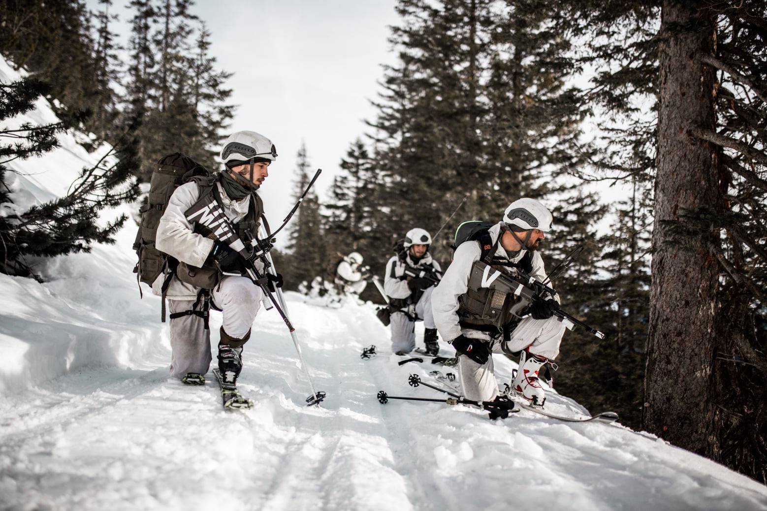 Eine Gruppe der Infanterie auf Schi übt auf einem verschneiten Waldweg
